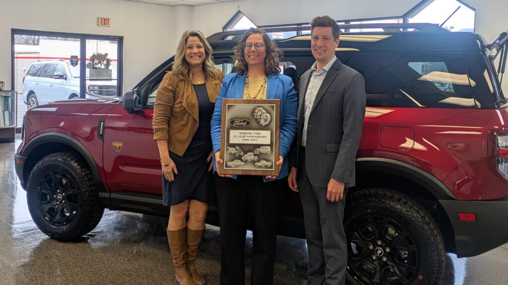 Emily Marlow receiving a 25-year anniversary plaque from Ford representatives at Marlow Ford